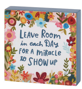 “Leave room in each day for a miracle to show up” block sign